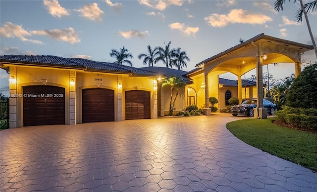 view of front of house featuring a garage, decorative driveway, stucco siding, and a tile roof