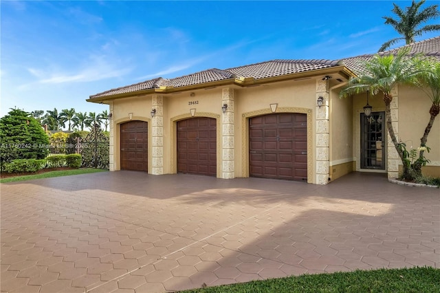 exterior space featuring a tiled roof, an attached garage, and stucco siding