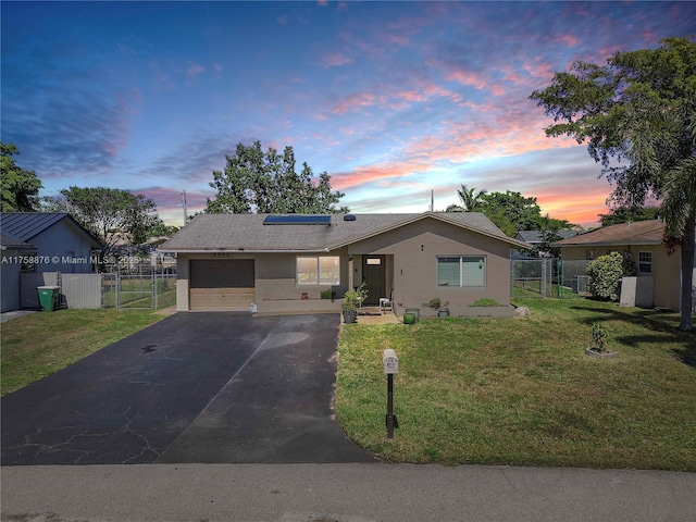 ranch-style home with fence, roof mounted solar panels, a lawn, a garage, and a gate