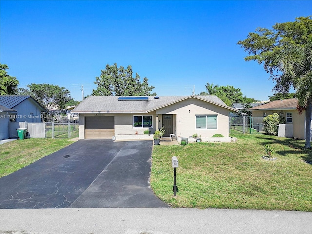 ranch-style home featuring solar panels, fence, a front yard, a garage, and a gate