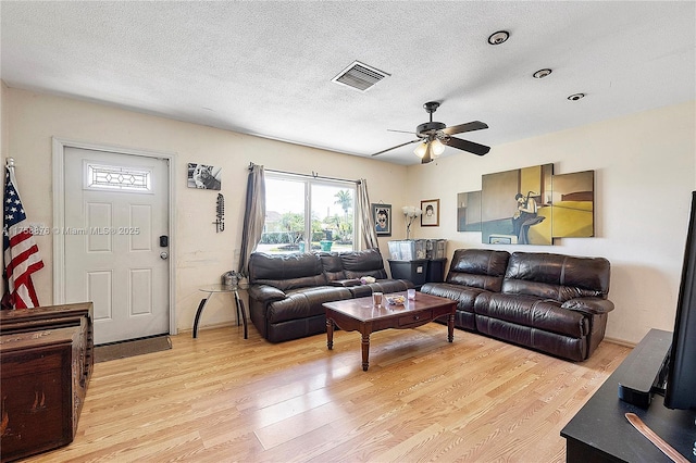 living room featuring visible vents, a textured ceiling, and light wood-type flooring