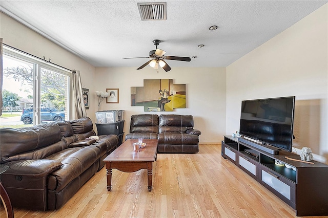 living area with visible vents, a textured ceiling, ceiling fan, and light wood finished floors