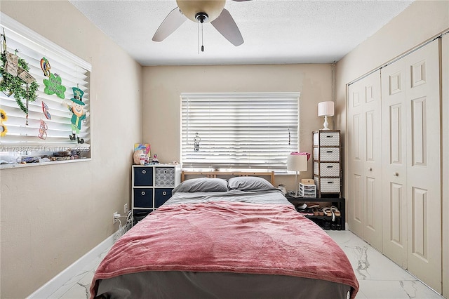 bedroom with a closet, marble finish floor, a textured ceiling, and baseboards