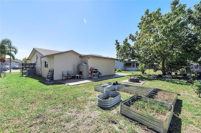 back of house with central air condition unit, a lawn, stucco siding, and a garden