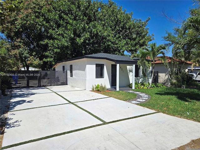 view of front facade with a front yard, fence, and stucco siding