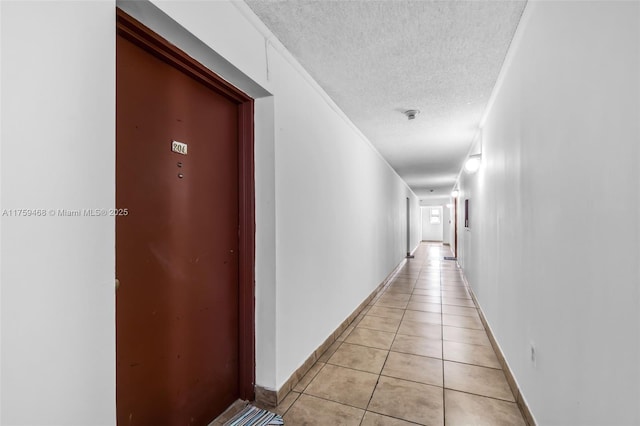 hall featuring ornamental molding, light tile patterned floors, baseboards, and a textured ceiling