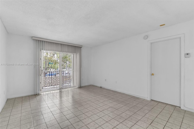 unfurnished room with a textured ceiling and baseboards