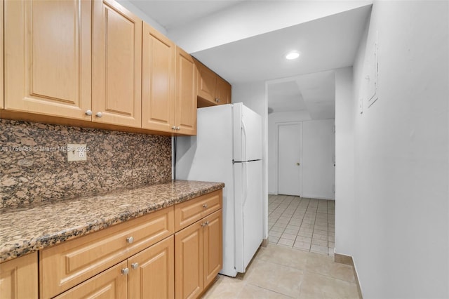 kitchen with light brown cabinets, light stone countertops, decorative backsplash, freestanding refrigerator, and light tile patterned flooring