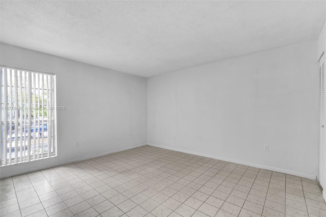 unfurnished room featuring a textured ceiling and baseboards