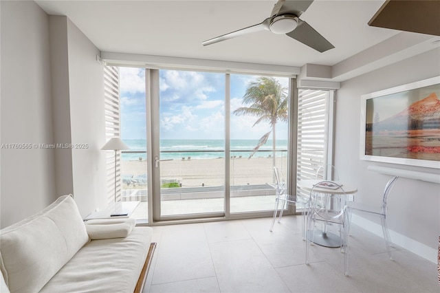 interior space featuring plenty of natural light, floor to ceiling windows, a ceiling fan, and a water view