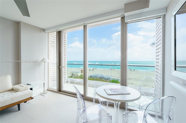 dining room with expansive windows, a water view, and a beach view