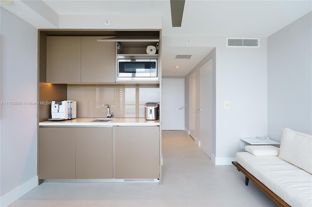 kitchen featuring stainless steel microwave, gray cabinets, visible vents, and a sink