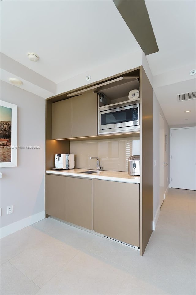 kitchen with stainless steel microwave, visible vents, gray cabinets, and light countertops