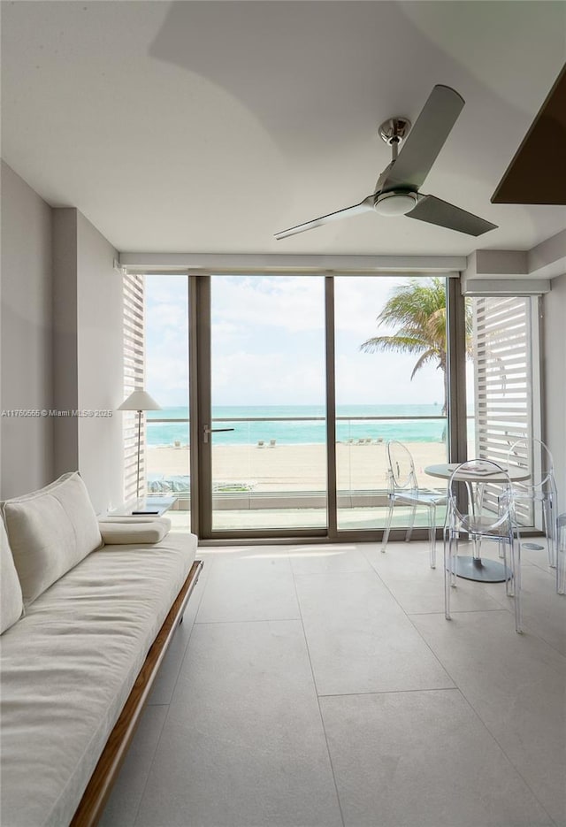 unfurnished bedroom featuring floor to ceiling windows, a beach view, ceiling fan, and a water view