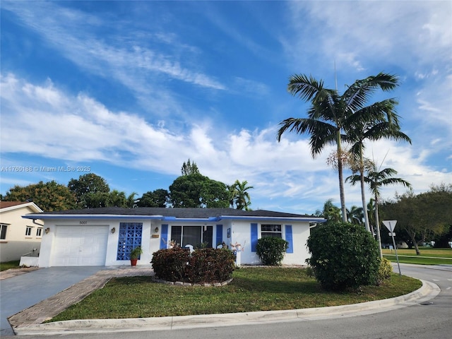 ranch-style home with stucco siding, a front yard, a garage, and driveway