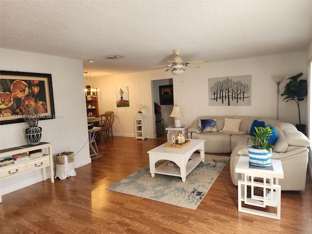 living area with visible vents, baseboards, ceiling fan, wood finished floors, and a textured ceiling