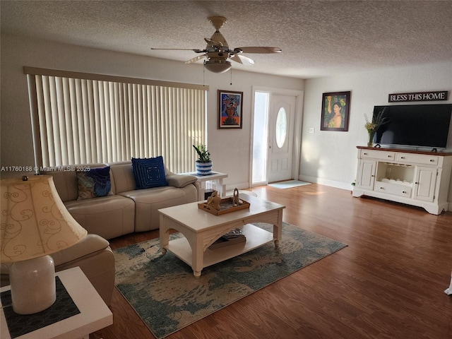 living area with ceiling fan, baseboards, a textured ceiling, and wood finished floors