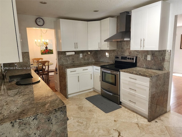 kitchen featuring dark stone counters, stainless steel electric range, decorative backsplash, white cabinetry, and wall chimney exhaust hood