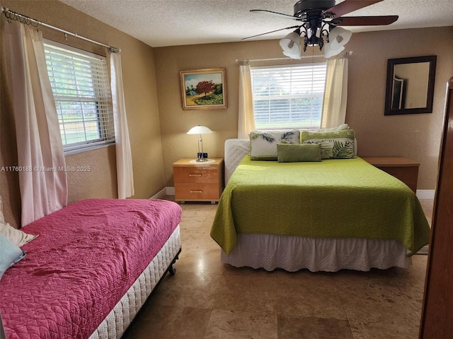 bedroom with ceiling fan, multiple windows, baseboards, and a textured ceiling