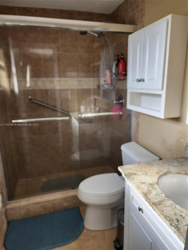 bathroom featuring toilet, a stall shower, and vanity