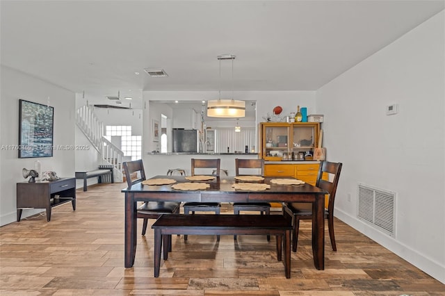 dining room featuring visible vents, light wood-style floors, and stairway