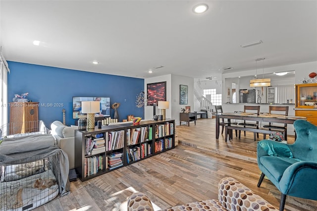 sitting room with stairs, recessed lighting, and wood finished floors