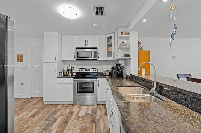 kitchen with visible vents, light wood-style floors, white cabinets, stainless steel appliances, and a sink