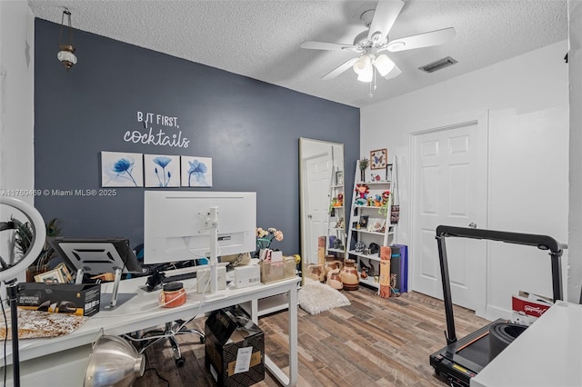 office featuring ceiling fan, visible vents, a textured ceiling, and wood finished floors