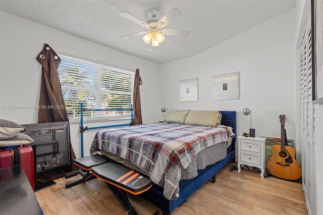 bedroom with a textured ceiling, ceiling fan, and wood finished floors