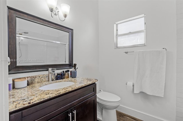 full bathroom featuring toilet, wood finished floors, baseboards, walk in shower, and vanity