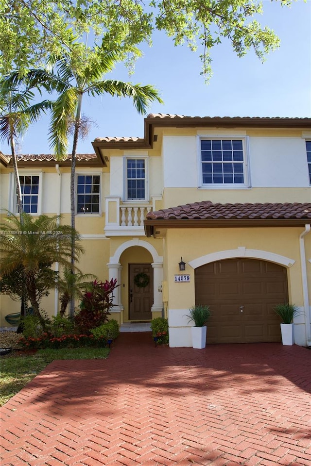 view of front of house with a tiled roof, decorative driveway, an attached garage, and stucco siding