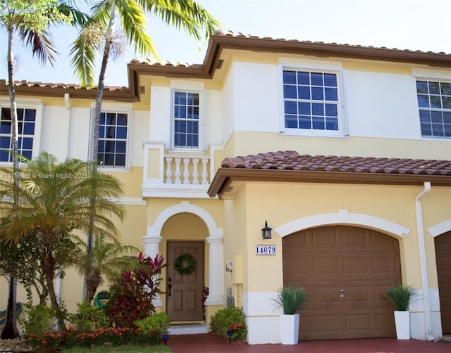 mediterranean / spanish house featuring an attached garage, driveway, and stucco siding