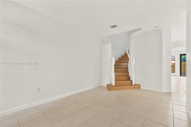 empty room with light tile patterned floors, stairway, baseboards, and visible vents