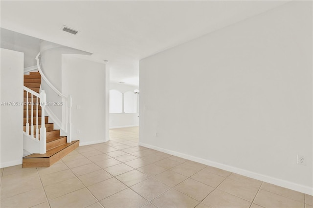 spare room with stairway, light tile patterned floors, baseboards, and visible vents