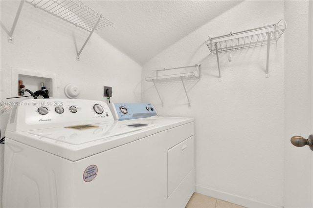 laundry area featuring a textured ceiling, washing machine and dryer, light tile patterned flooring, baseboards, and laundry area