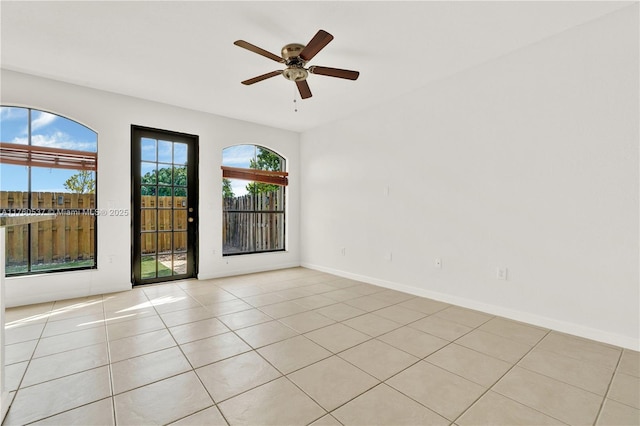 spare room with light tile patterned floors, a ceiling fan, and baseboards