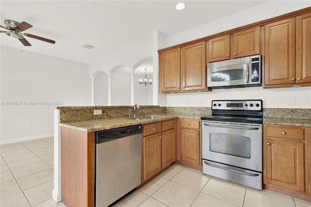 kitchen with visible vents, a sink, stainless steel appliances, light tile patterned flooring, and brown cabinetry