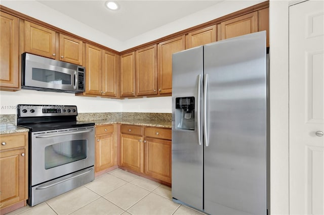 kitchen featuring light stone counters, brown cabinetry, light tile patterned floors, recessed lighting, and appliances with stainless steel finishes