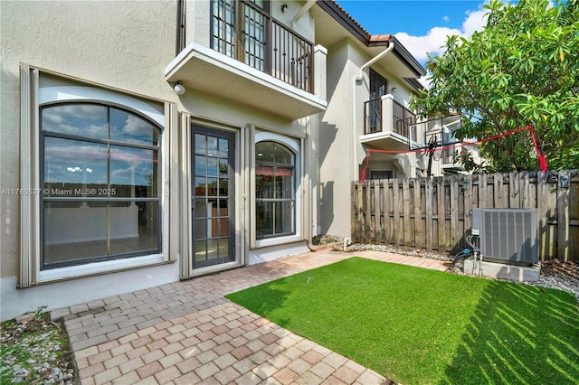 view of yard featuring central air condition unit, a patio, a balcony, and fence