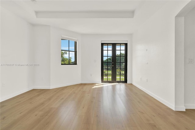 spare room featuring french doors, baseboards, and light wood finished floors