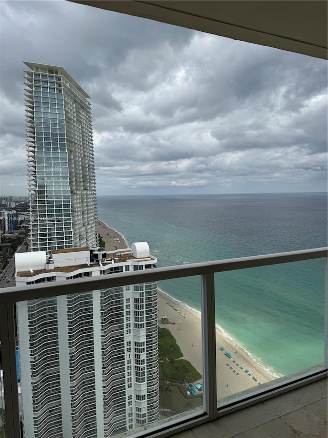 balcony with a water view and a view of the beach