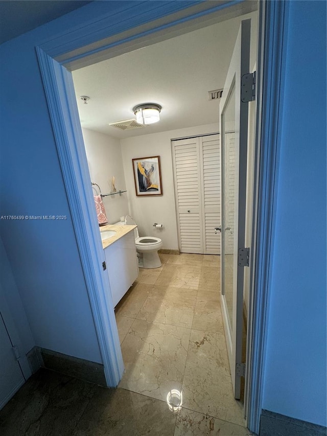 bathroom with vanity, toilet, and a closet