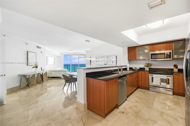 kitchen with appliances with stainless steel finishes, dark countertops, a peninsula, and brown cabinetry