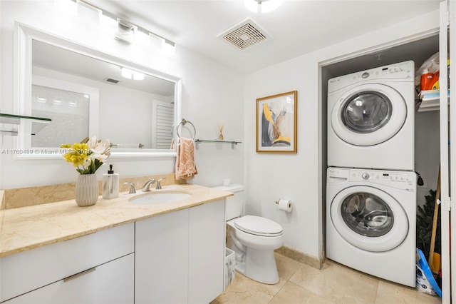 bathroom featuring stacked washer and clothes dryer, visible vents, toilet, vanity, and tile patterned flooring
