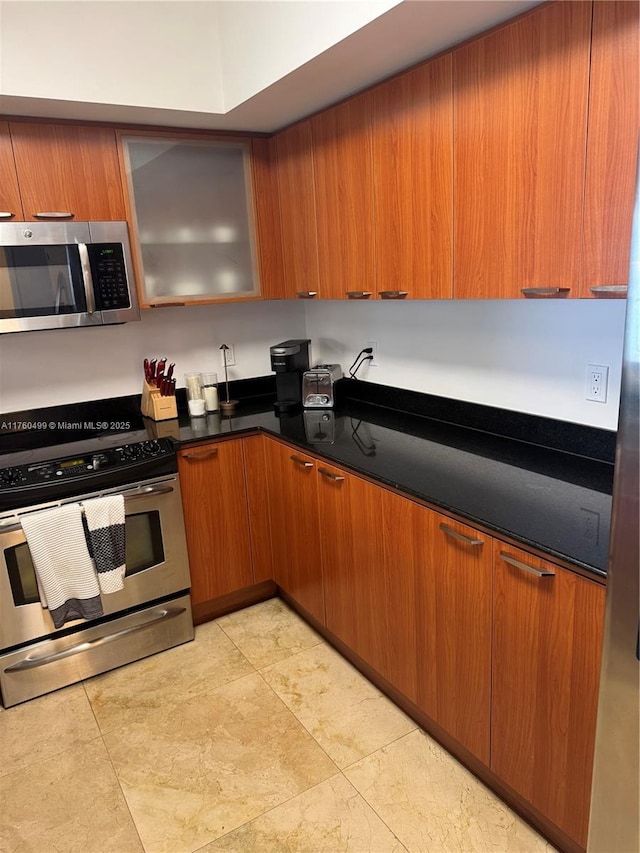 kitchen featuring stainless steel appliances, brown cabinets, and dark countertops