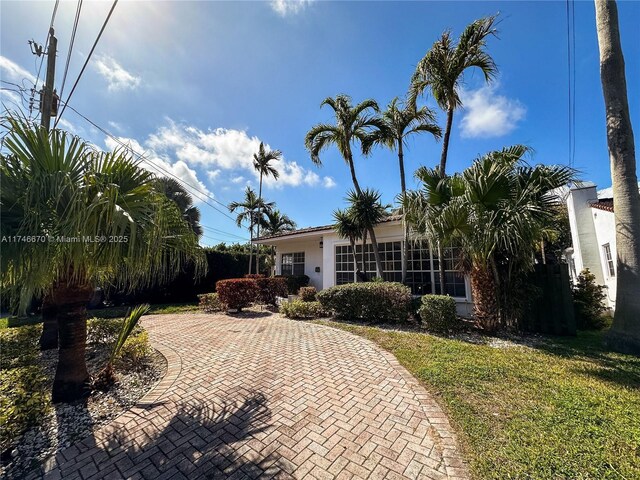 8926 Dickens Ave, Surfside, FL 33154 - obstructed view of property featuring a front lawn and stucco siding