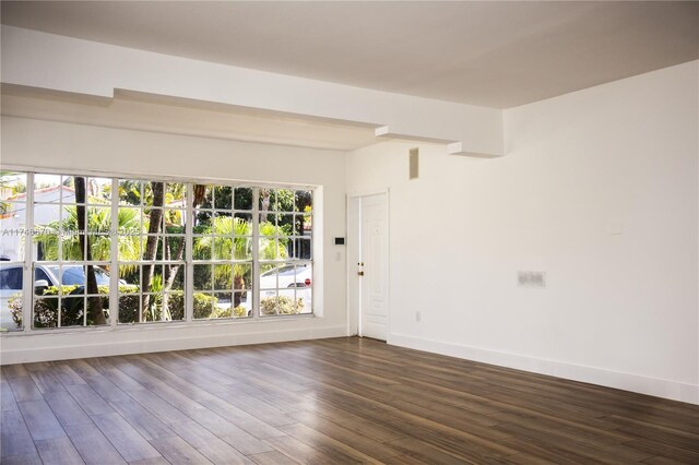 unfurnished room with baseboards and dark wood finished floors