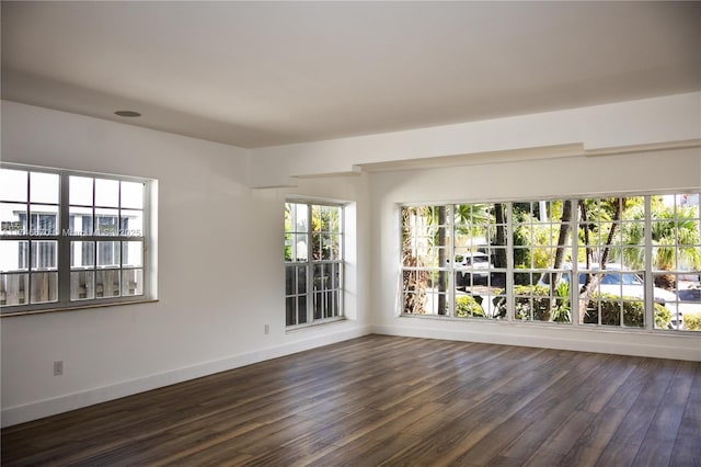 spare room with baseboards and dark wood-style flooring