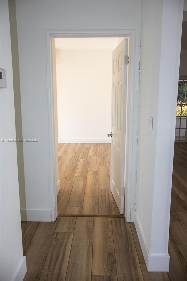 corridor featuring baseboards and wood finished floors