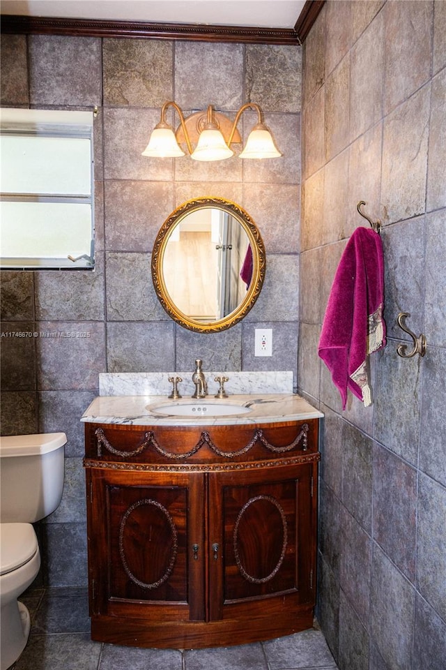 bathroom with tile walls, tile patterned flooring, toilet, and vanity